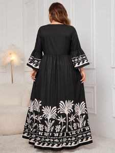 Detail of flared sleeves and bohemian palm tree print on a black flowing maxi dress