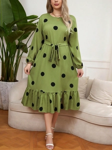 Close-up of green polka dot dress with waist tie and feminine ruffled hem detail