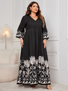 Detail of V-neck and bell sleeves on a black maxi dress with white palm leaf patterns