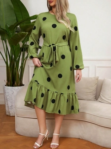 Detail of green polka dot dress with long sleeves, waist tie, and ruffled hem finish