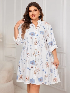 Detailed view of the button-down stand collar and blue floral print on the white dress