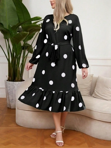 Close-up of long sleeve black polka dot dress featuring a tie-waist and ruffled hemline