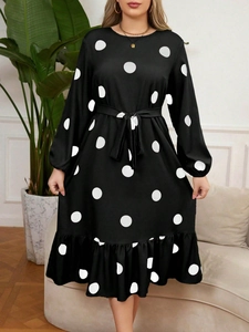 Close-up of black long sleeve polka dot dress with waist tie and ruffle hem detail