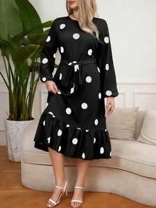 Detail view of long-sleeve polka dot dress featuring a tie waist and ruffled hemline