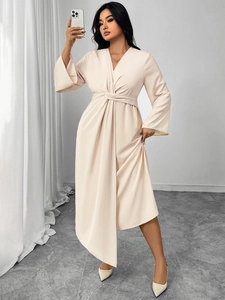 Detail of elegant beige long-sleeve dress with V-neckline and twisted waist design