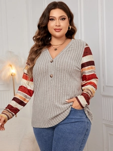 Detail of V-neck button design and gray ribbed fabric with striped patchwork sleeves