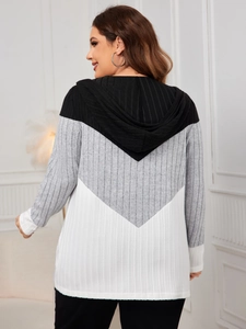 Detail of striped oversized hooded cardigan showing black, grey, and white patchwork knit