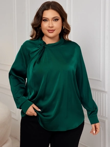 Detail view of the twisted high-neck design and sleek satin fabric on a dark green blouse