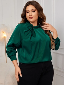 Detailed view of dark green satin shirt with elegant twist knot neck and pearl cuff buttons