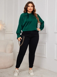 Detail of elegant dark green satin blouse with twisted neckline on plus size model