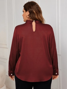 Detail of burgundy satin shirt featuring pearl buttons and a back teardrop cutout design