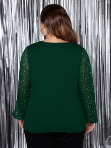 Dettaglio di maniche a sbuffo verde scuro con paillettes argentate e mesh su camicetta