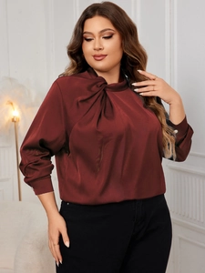 Detailed view of the elegant wine red satin blouse featuring a knot neckline and silky sheen