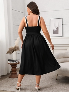 Detail of elegant black midi dress featuring a smocked back and striped woven straps