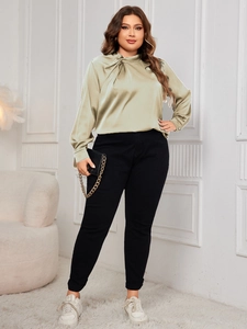 Detail of sage green satin shirt with elegant twist knot neckline and draped texture