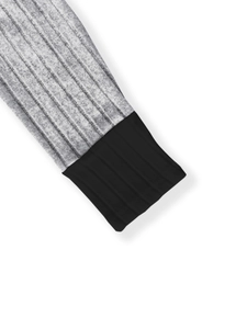 Detail shot of grey striped knit cardigan featuring a black ribbed cuff and neat stitching