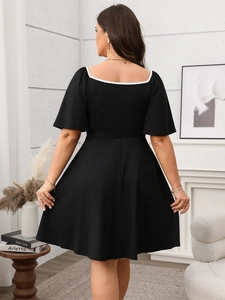 Back view of a plus-size black A-line dress with white square collar and bow detail