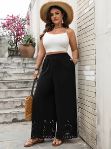 Detailed view of intricate laser-cut hollow pattern on black wide-leg trousers hem