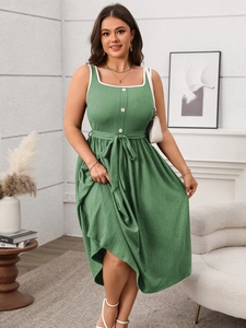 Detail of green maxi dress featuring white lace trim, buttons and a waist tie detail