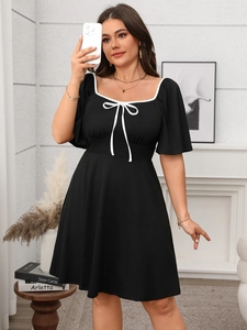 Close-up of retro square neckline with white piping and a bow on a black midi dress