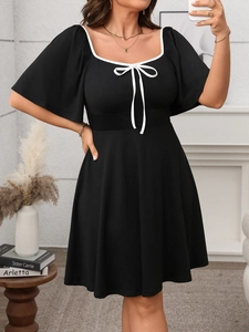 Close-up of square neckline with white contrast trim and bow detail on black dress