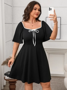 Detail of square neckline with contrast white trim and elegant bow tie on black dress