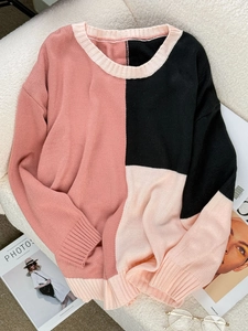 Detail of color-block knit sweater with pink, black, and beige textures on a soft rug