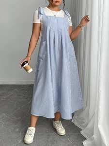 Close-up of blue and white striped pinafore dress featuring side pockets and bow shoulder straps