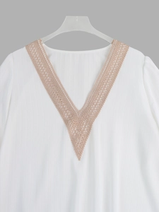 Detail of V-neck white blouse featuring geometric lace patchwork and textured fabric