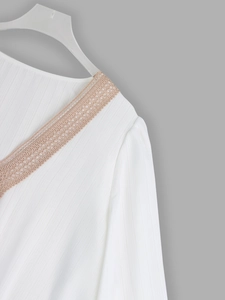 Detail of V-neck white shirt with floral lace trim and vertical ribbed fabric texture