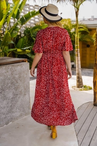 Détail d'une robe maxi à fleurs rouges avec taille haute et vue de dos au jardin