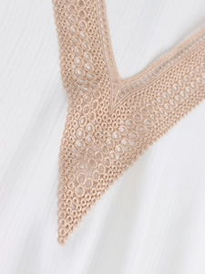 Detailed close-up of V-neckline with intricate lace trim on a white textured blouse