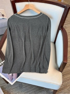 Dettaglio top girocollo grigio scuro con cuciture a contrasto su maniche raglan