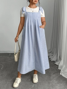 Detail of blue striped overall dress featuring shoulder ties and large functional pockets