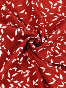 Gros plan détaillé du tissu rouge à motifs de feuilles blanches et plis souples