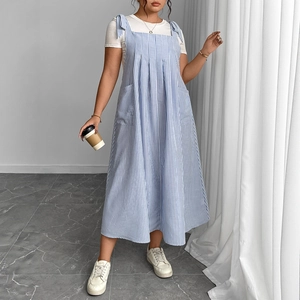 Relaxed blue striped overall dress with tie shoulders and pockets over a white t-shirt