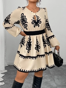 Detail of bohemian print on long sleeve dress with cutout neckline and cinched waistline