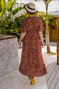 Vue de dos d'une robe longue rouge brique à taille haute avec motifs de feuilles blanches