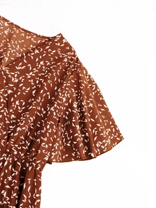 Détail d'une robe d'été à col en V avec imprimé floral blanc et manches courtes volantées