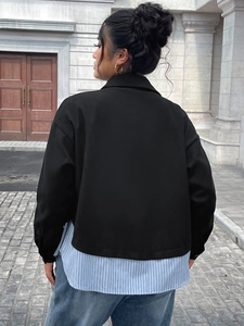 Dettaglio della giacca corta nera sopra una camicia lunga a righe bianche e blu