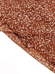 Détail du tissu floral marron avec imprimé feuilles blanches et ourlets de qualité