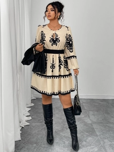 Detail of cream long sleeve dress with black floral embroidery and waist cinch feature