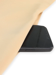 Detail view of khaki trench coat side pocket showing its depth with a smartphone