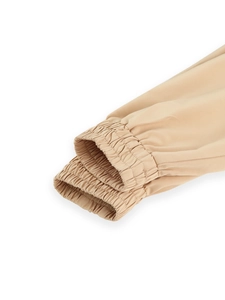 Close-up of elastic cuffs on light khaki long trench coat with smooth fabric texture