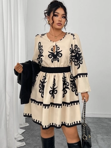Detail of embroidered mini dress with bubble sleeves and black floral patterns on cream fabric