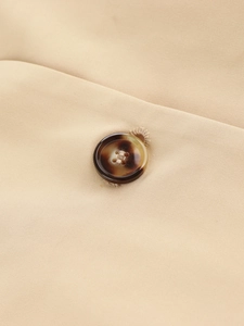 Close-up of tortoise shell buttons and khaki woven fabric texture on a long trench coat