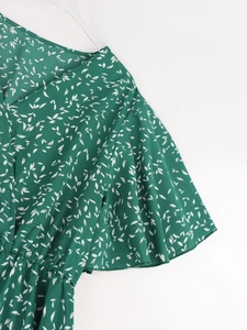 Détails du col en V, des manches à volants et de l'imprimé floral vert sur la robe d'été