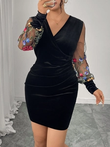 Detail of V-neck velvet dress showing black fabric and colorful floral mesh sleeves