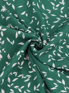 Gros plan sur tissu floral vert foncé avec motifs de feuilles blanches et drapé fluide