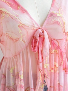 Detail of V-neck floral mesh top featuring pink marble print and gold trim accents